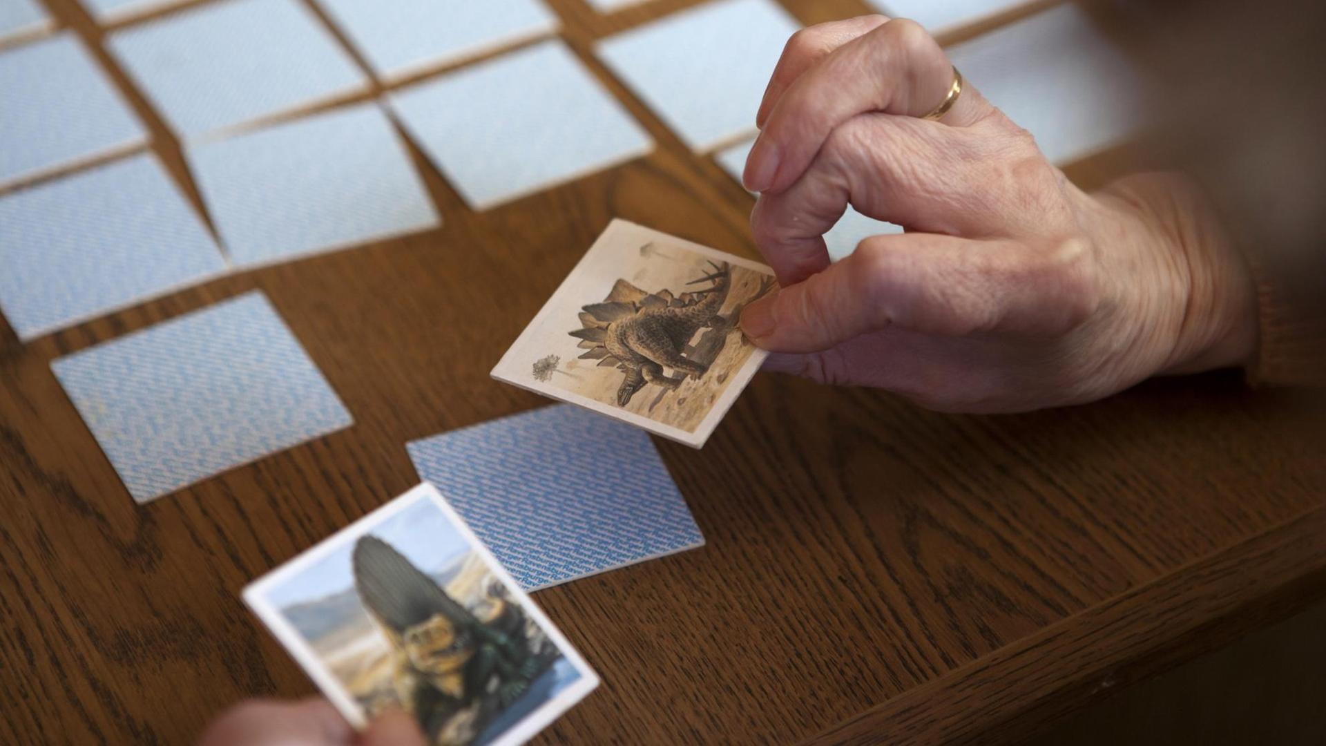 Eine Seniorin spielt Memory: Zu sehen sind die Hände und Spielkarten.