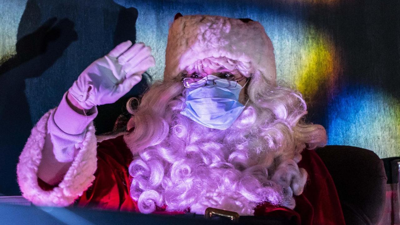Ein verkleideter Weihnachtsmann mit Covidmaske winkt in einem drive-through Christmas event in Seattle, USA.