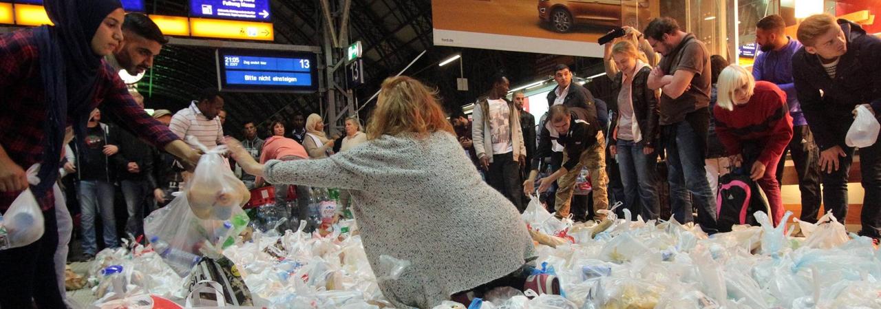 Eine ehrenamtliche Helferin verteilt am Frankfurter Bahnhof Essenspakete an Flüchtlinge.