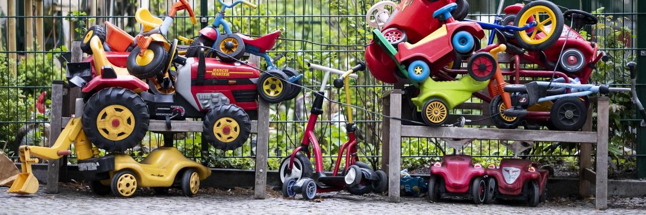 Bobbycars und Kinderfahrräder stapeln sich angeschlossen vor einer Kita in Berlin-Wilmersdorf.