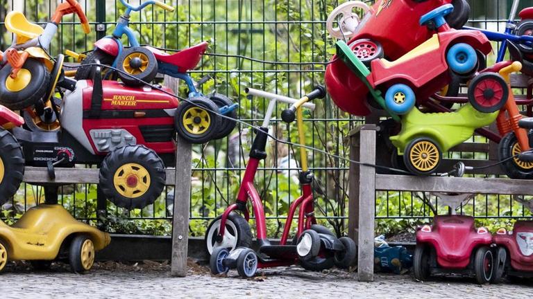 Bobbycars und Kinderfahrräder stapeln sich angeschlossen vor einer Kita in Berlin-Wilmersdorf.