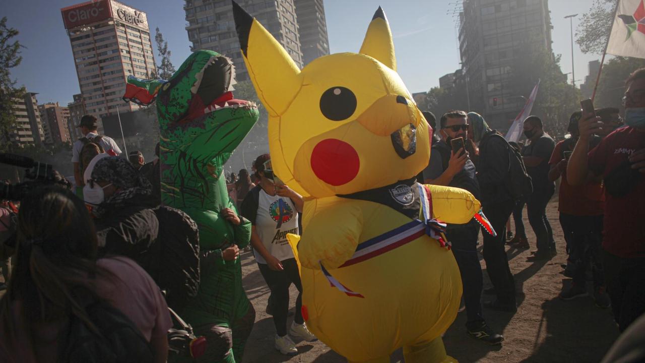 Als Dinosaurier und Pikachu verkleidete Demonstranten nehmen an einem regierungsfeindlichen Protest auf der Plaza de la Dignidad teil.