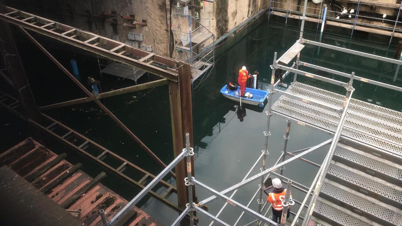 Einsturzstelle des Kölner Stadtarchivs ist mit Wasser vollgelaufen, darauf sind Bauarbeiter in Booten.