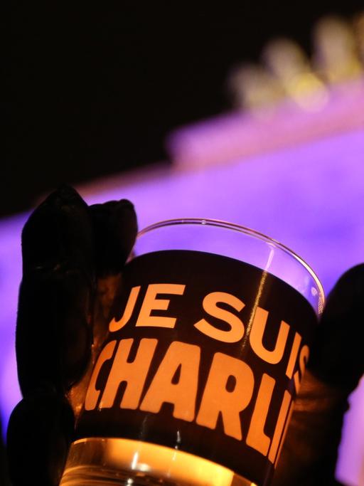 Eine Glas mit einer Kerze und der Aufschrift Je suis Charlie wird am 13.01.2015 in Berlin vor dem Brandenburger Tor gehalten.