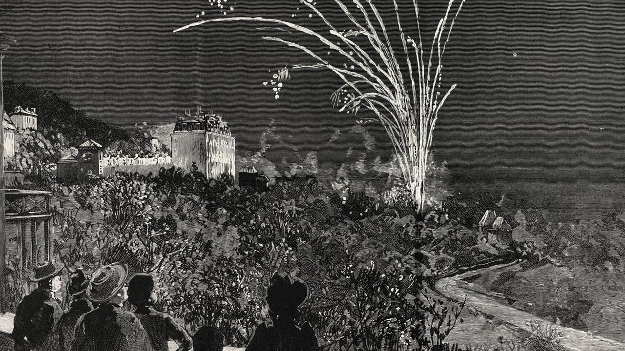 Zeitgenössischer schwarzweiss Druck mit dem Blick auf das festlich beleuchtete Grand Hotel in Grasse und das Feuerwerk zu Ehren von Prinzessin Beatrice. Im Vordergrund sind Silhouetten von Zuschauern zu sehen.