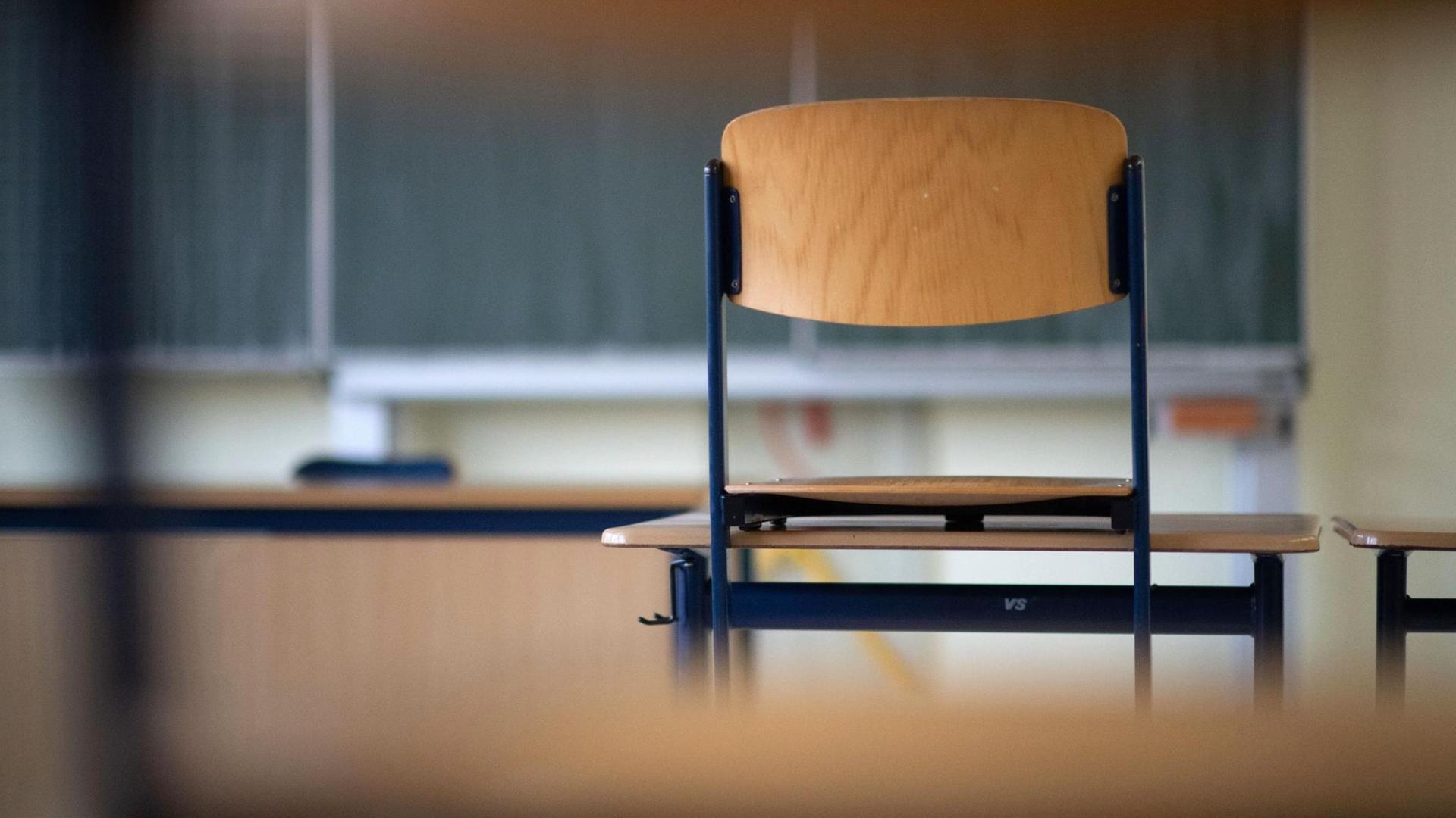 Ein Stuhl steht in einem leeren Klassenzimmer einer Schule auf einem Tisch. Ein Stuhl steht in einem leeren Klassenzimmer einer Schule auf einem Tisch.
