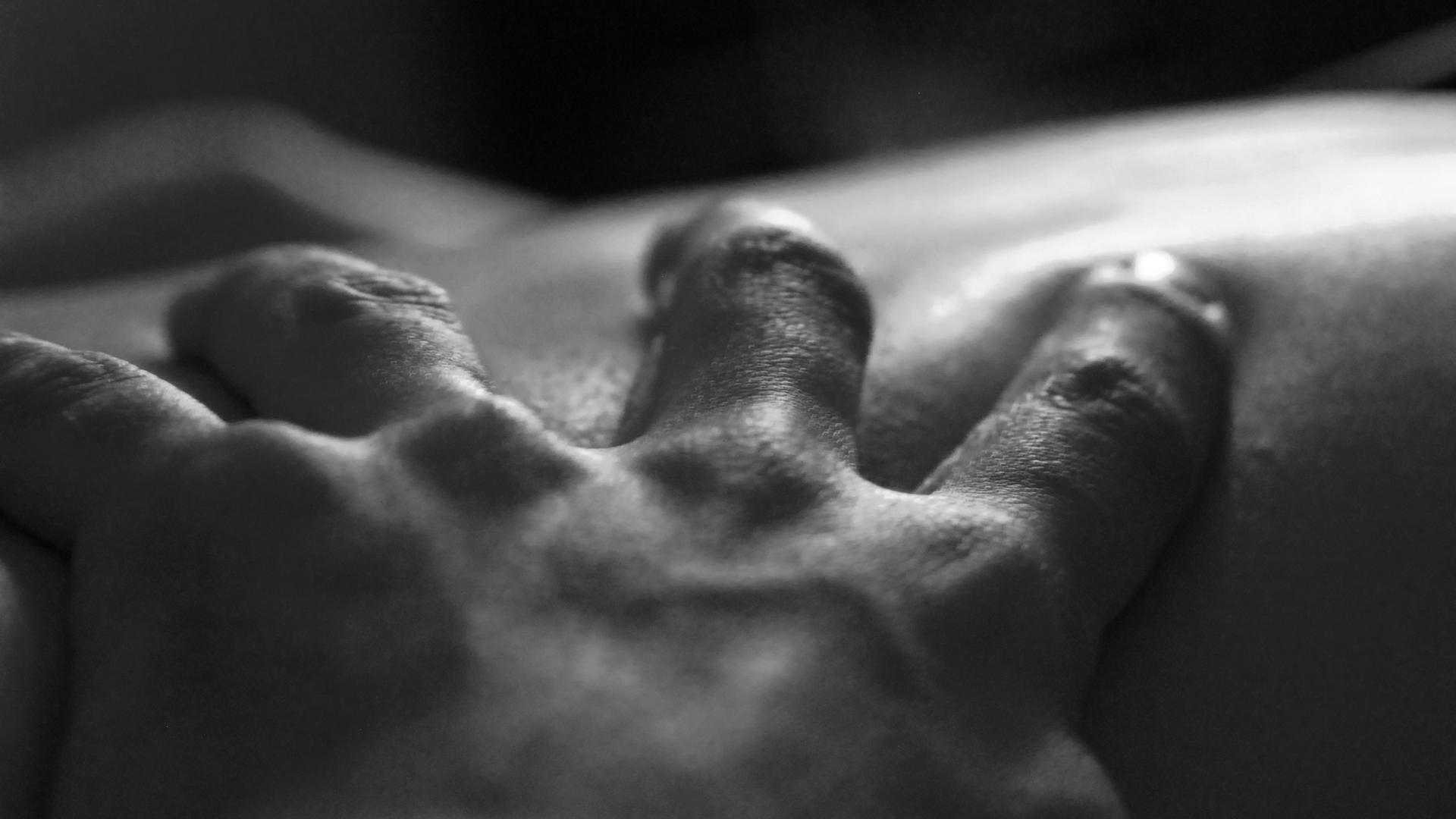 Eine Hand greift in die Haut eines anderen Menschen.