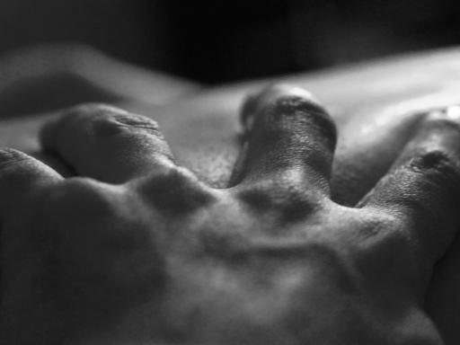 Eine Hand greift in die Haut eines anderen Menschen.
