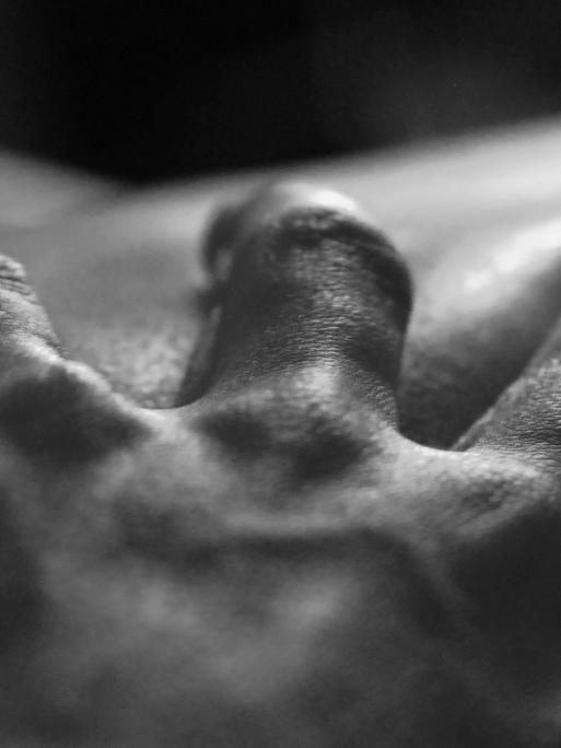 Eine Hand greift in die Haut eines anderen Menschen.
