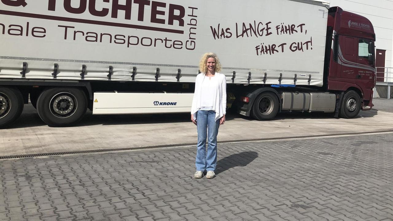 Das Foto zeigt die Firmenchefin Romy Lange von der Spedition Lange und Töchter vor einem Lkw im Hof des Unternehmens.