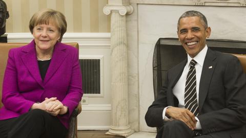 Bundeskanzlerin Angela Merkel und US-Präsident Barack Obama im Oval Office. Beide lachen in die Kameras.