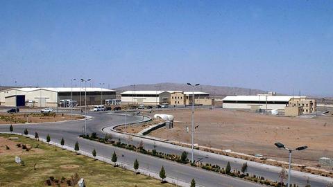 Blick aus der Ferne auf Natans, das in einer sandigen Umgebung liegt. Eine Straße führt dorthin. 