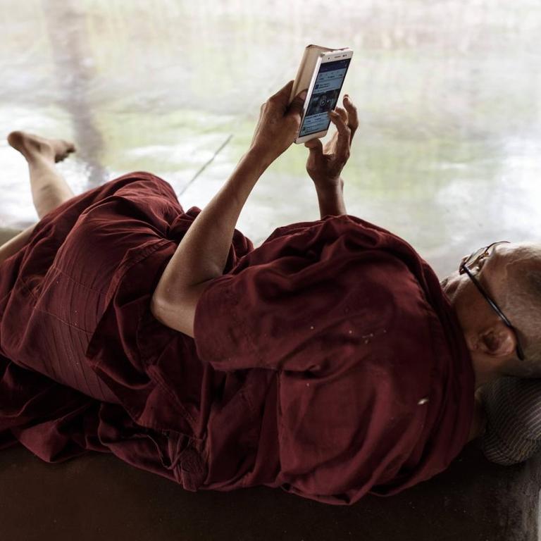 Ein buddhistischer Mönche besucht die Seite von Facebook auf seinem Samrtphone in der Kawhnat Pagode - Kor Nat, Myanmar, 2017