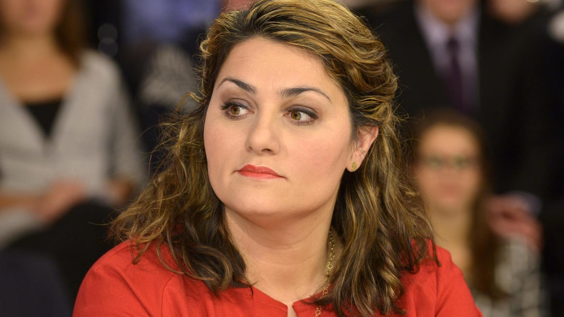 Eine junge Frau mit langen Haaren, die aus dem Mittleren Osten stammen könnte, schaut nachdenklich zur Seite. Sie trägt ein rotes Jacket. Es ist die Islamwissenschaftlerin Lamya Kaddor.