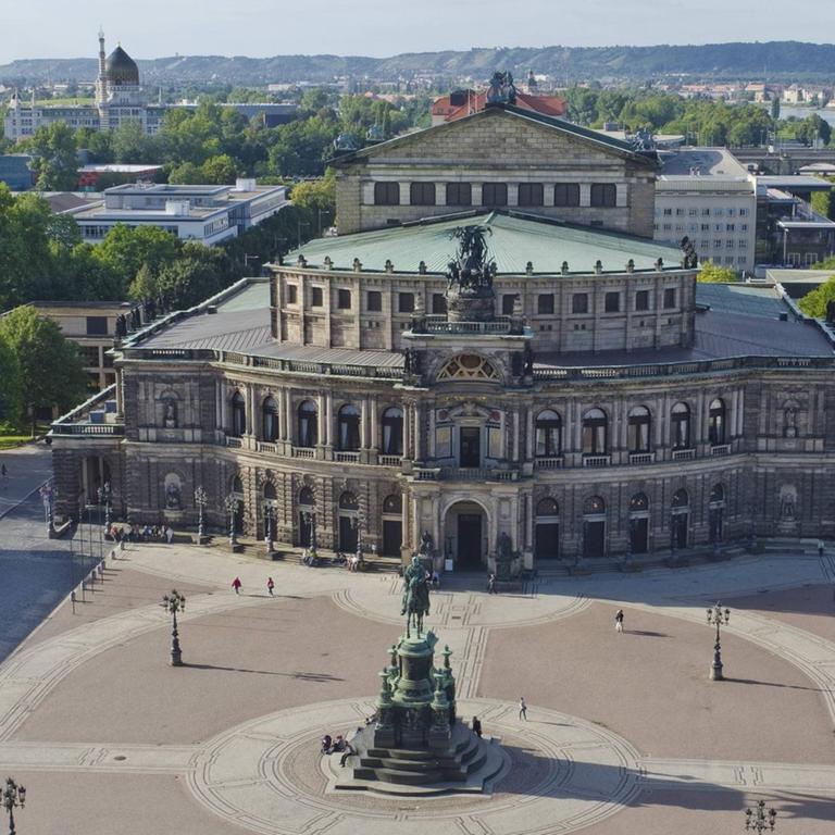 Luftbild der Semperoper, die hinter einem großzügigen runden Platz liegt. Im Hintergrund die Elbe