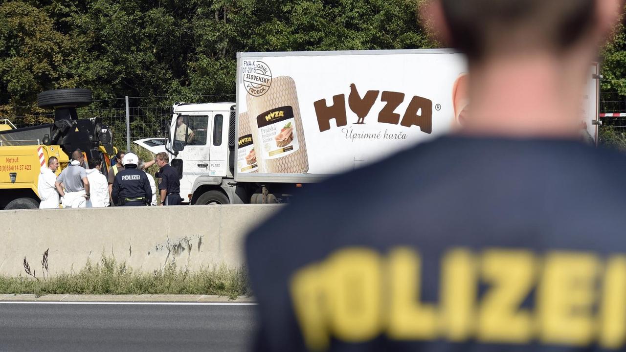 Forensiker untersuchen von außen einen Lkw, in dem zahlreiche tote Flüchtlinge liegen.