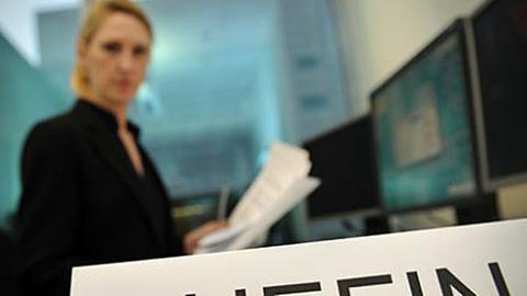 Eine Frau sitzt an einem Arbeitsplatz, vor ihr steht das Schild mit der Aufschrift "Chefin"