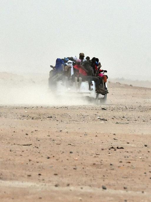Mehrere Pick-ups, auf denen dutzende Migranten sitzen, fahren durch die Wüste von Agadez im Niger in Richtung Liyben (1.6.2015).
