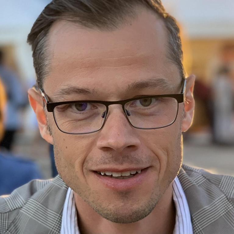 Ein Mann mit kurzen Haaren und Brille schaut in die Kamera.