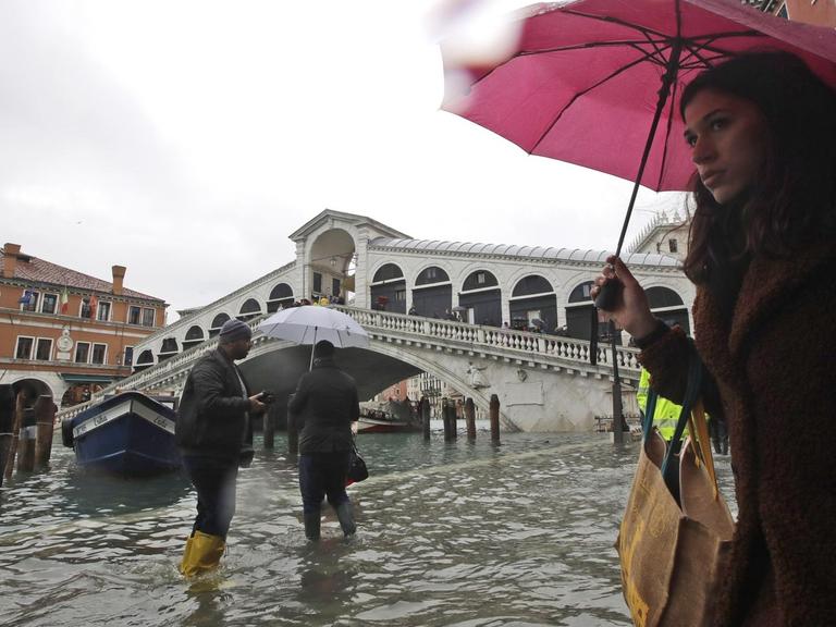 Italien, Venedig: Passanten gehen in der Nähe der Rialto-Brücke durch das Hochwasser.
