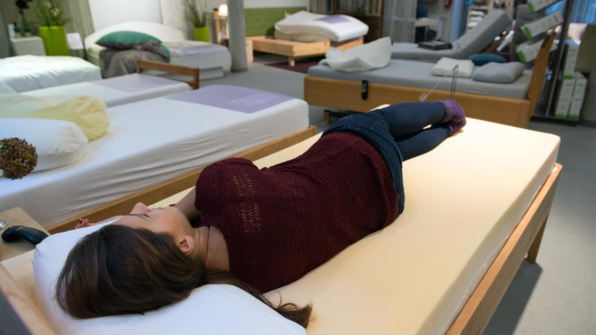 Eine Kundin testet in einem Bettenhaus in Berlin die Liegeeigenschaften einer Matratze mit Viscoschaum.
