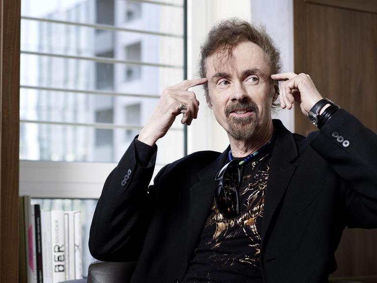 Porträtdes US-Schriftstellers von T.C. Boyle, der sich mit beiden Zeigefingern an die Stirn tippt.