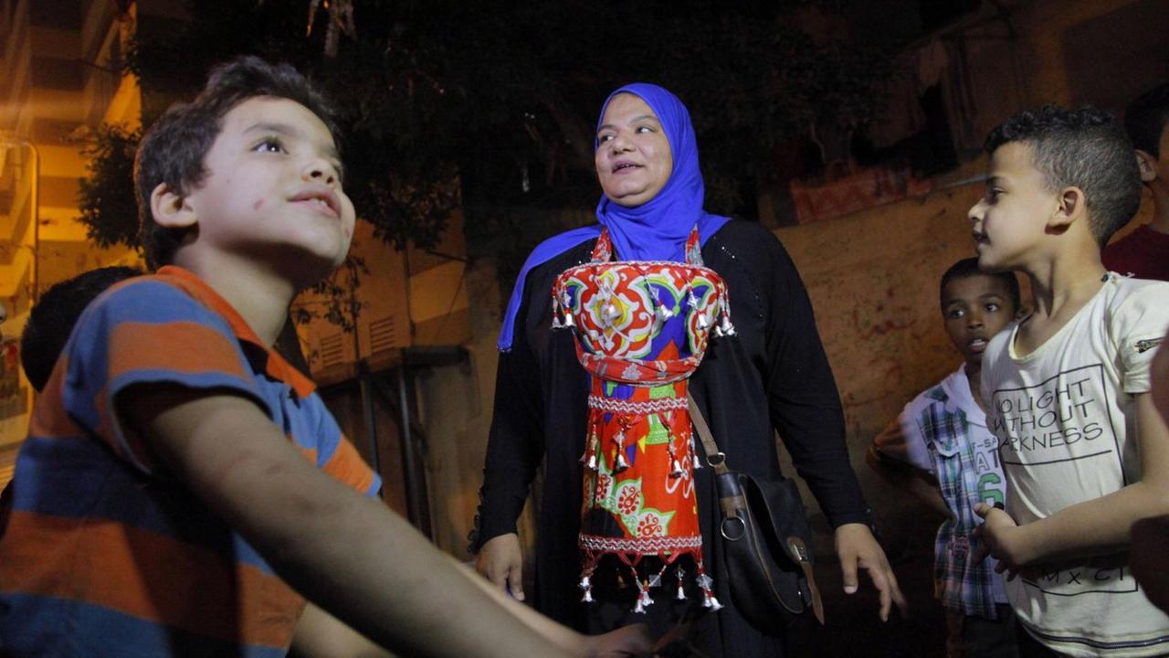 Kinder und eine Frau stehen auf einer Straße während des Ramadans in Kairo.