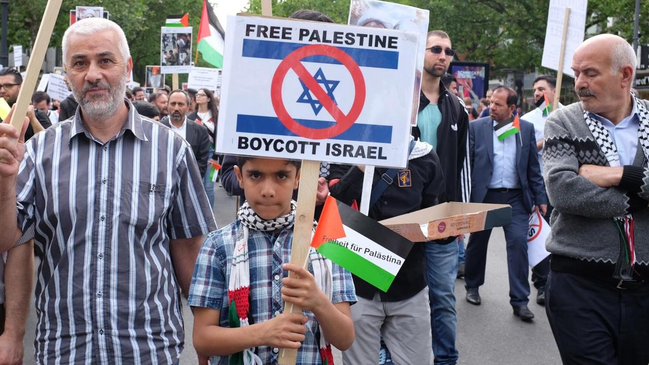 Ein Junge hält ein Schild hoch mit einem Boykott-Aufruf gegen Israel. Am Al-Kuds-Tag demonstrieren Palästinenser auf dem Berliner Kurfürstendamm gegen sogenannte Zionisten und gegen Israel.