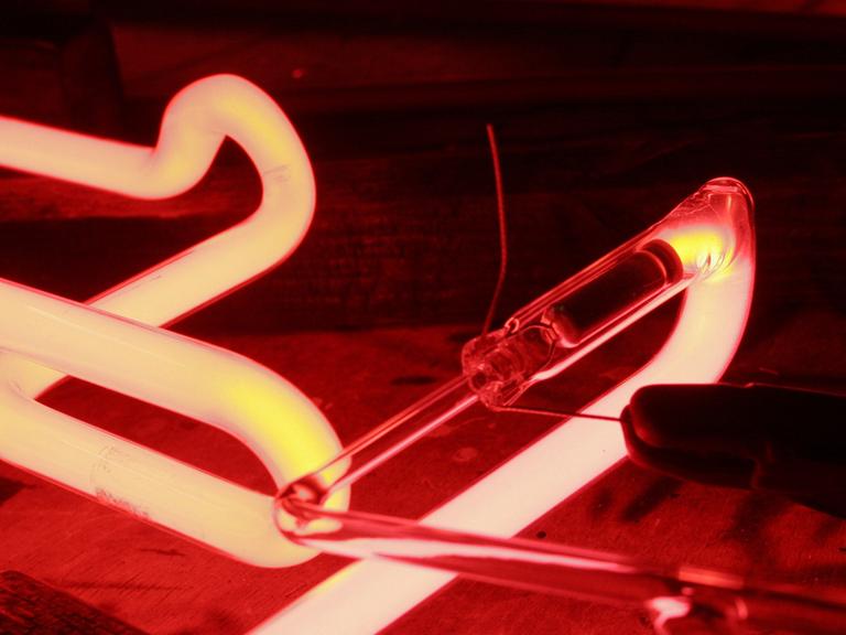 In eine Glasröhre für eine Leuchtreklame wird Neonleuchtstoff eingebrannt.