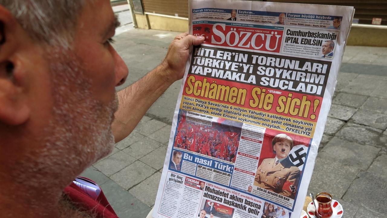Ein Mann blickt in die türkische Tageszeitung "Sözcü", die Bundeskanzlerin Merkel mit Hitlerbart und Hakenkreuz auf der Titelseite abbildet und schreibt "Schämen Sie sich".
