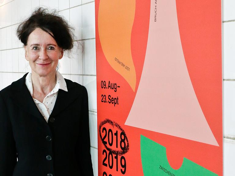 Ruhrtriennale-Intendantin Stefanie Carp bei der Programmpräsentation, rechts ein Plakat zur Ruhrtriennale 2018-2020