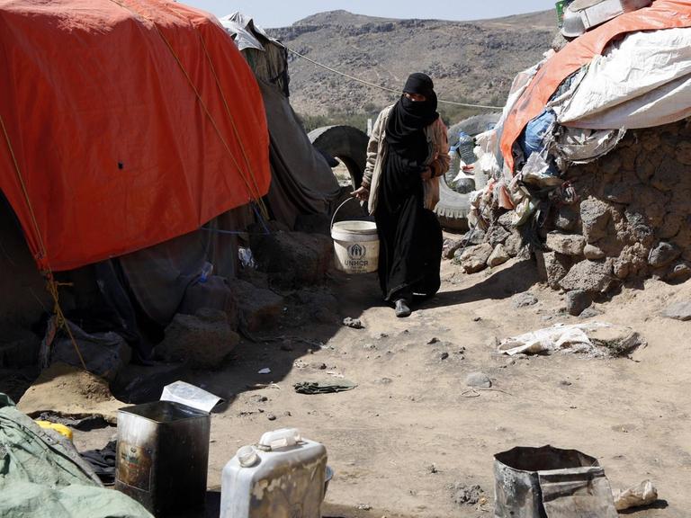 Eine Frau zwischen improvisierten Zelten in einem Flüchtlingscamp im Jemen