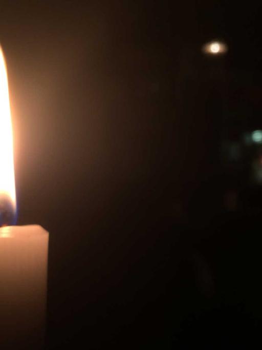 Eine Kerze brennt in der Dunkelheit.