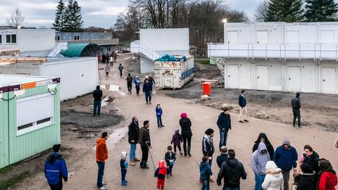 Flüchtlinge stehen im Dezember 2015 in einer Asylbewerberunterkunft in Kiel auf einem Platz zwischen Wohncontainern.