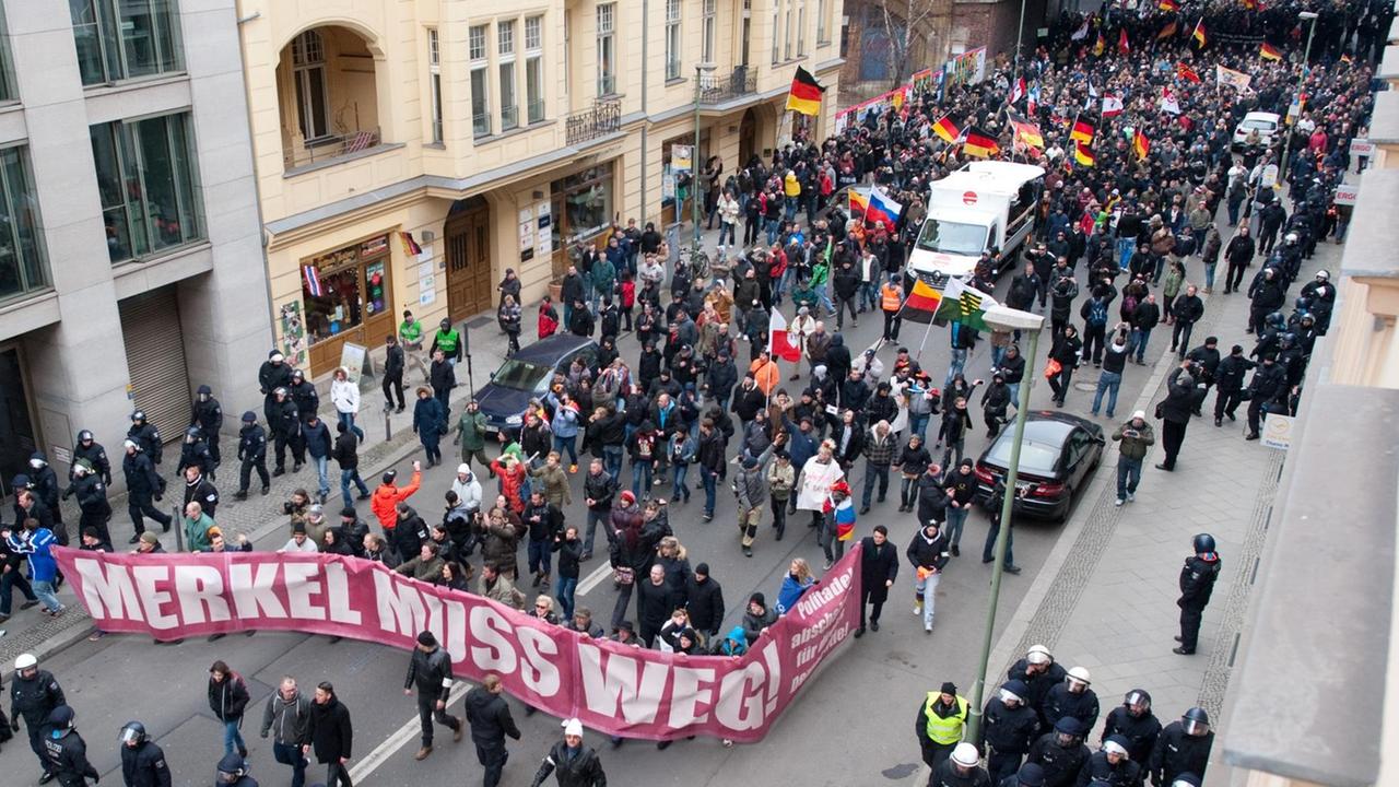 Blick von oben auf die Demonstranten, die ein Transparent mit der Aufschrift "Merkel muss weg" tragen