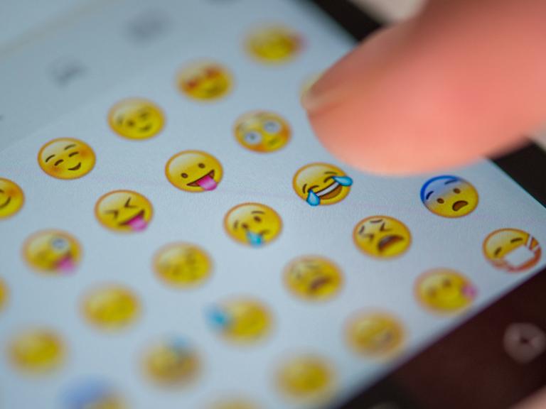 Ein Smartphone-Nutzer tippt auf ein Emoji, um es in eine WhatsApp-Nachricht einzufügen.