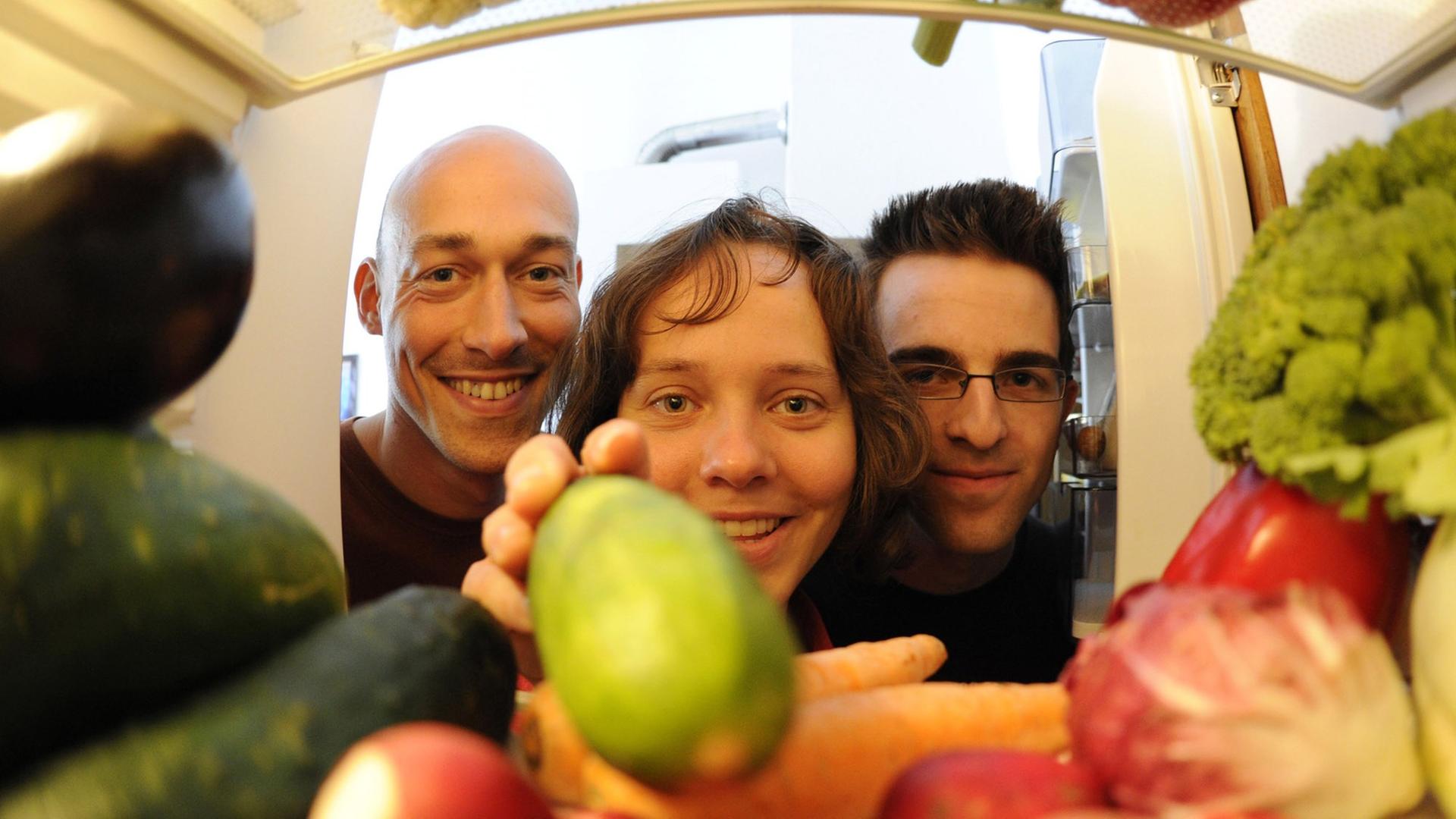 Die sich vegan ernährenden Robert Kresse (l), Silke Bott (M) und Robert Elzer (r) blicken in ihrer Wohngemeinschaft in Karlsruhe in den mit Gemüse gefüllten Kühlschrank (Foto vom 04.08.2010).