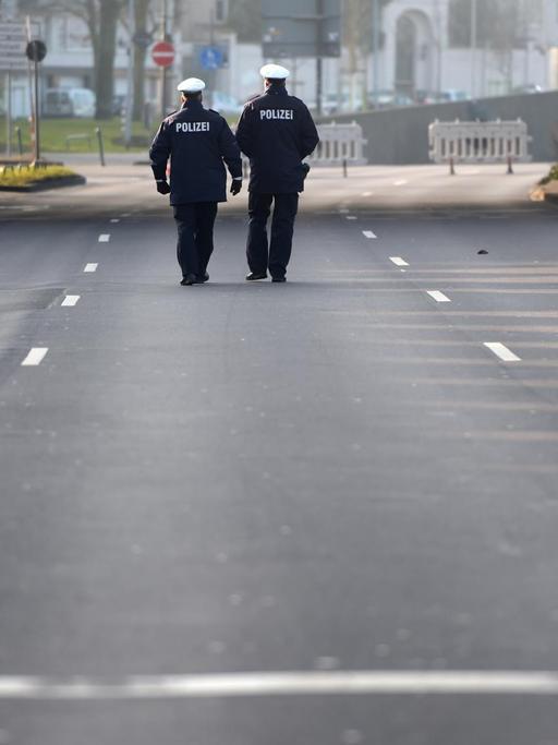 Polizisten gehen in Düsseldorf über eine gesperrte Strasse.