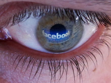 Der Schriftzug "Facebook" spiegelt sich auf dem Auge eines Mannes.