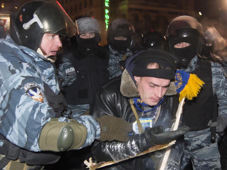 Polizisten mit einem Demonstrenten am 11. Dezember 2013 in Kiew