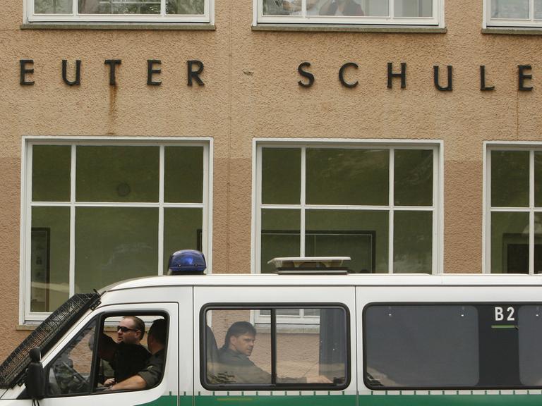 Polizisten laufen an Polizei-Einsatzfahrzeugen vorbei, die vor der Ernst-Reuter Schule in Berlin geparkt sind. Das Foto ist vom Mai 2007. Damals kam es zu einem Zwischenfall, bei dem ein 21-Jähriger und ein 16-Jähriger durch ein Messer verletzt wurden.