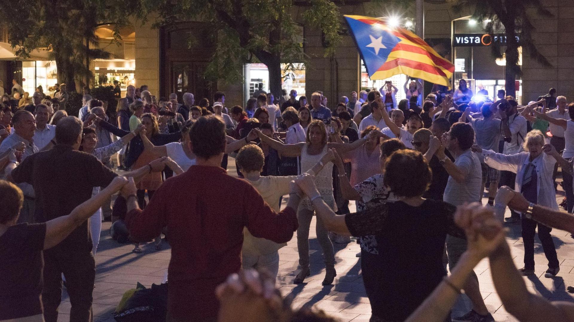 Katalanen tanzen Sardana in Barcelona mit der Fahne der katalanischen Unabhängigkeitsbewegung