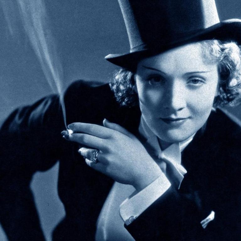 Schauspielerin Marlene Dietrich. Gekleidet in einem Frack und mit Zylinder auf dem Kopf.