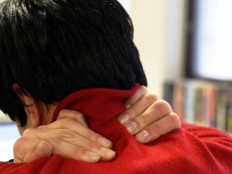 Ein junge Frau mit Verspannungen und Schmerzen im Halswirbelbereich.