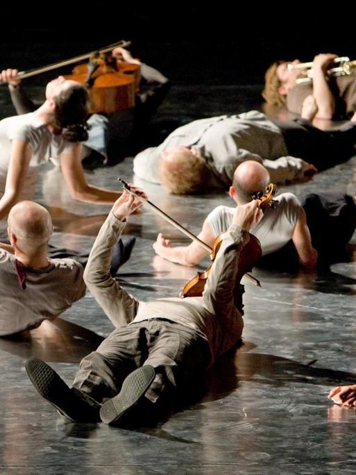 ARCHIV - Mitglieder des Ensemble Modern liegen während der Uraufführung von Wolfgang Rihms "Jagden und Formen (Zustand 2008)" auf der Bühne.