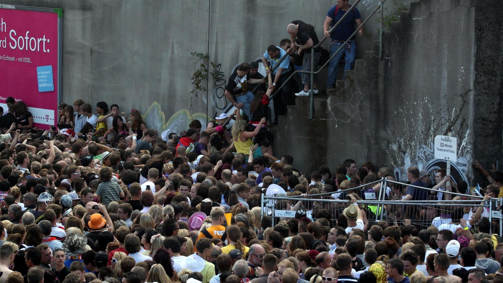 Menschen stehen dichtgedrängt vor und auf einer Treppe an einem Tunnelausgang in Duisburg.