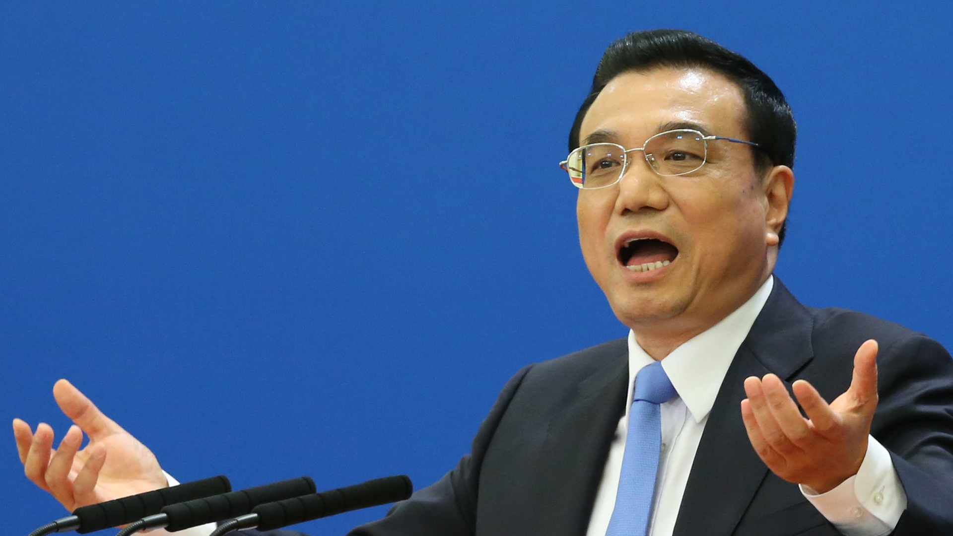 Li spricht gestikulierend vor blauem Hintergrund in mehrere Mikrofone. Er hält im Rahmen einer Pressekonferenz sein Schlusswort zum Volkskongress in Peking.