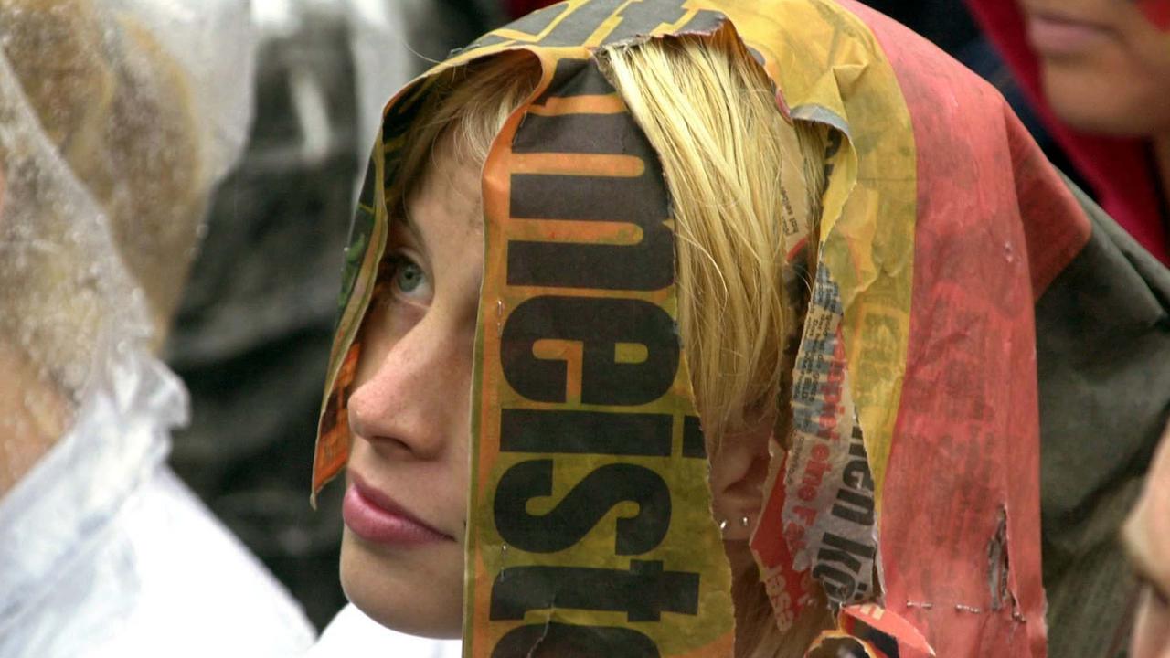 Ein weiblicher Fußball-Fan hat sich den Kopf mit einer zerrissenen "Weltmeister-Sonderseite" bedeckt und schaut enttäuscht auf die Großbildleinwand in Hamburg St. Pauli. 