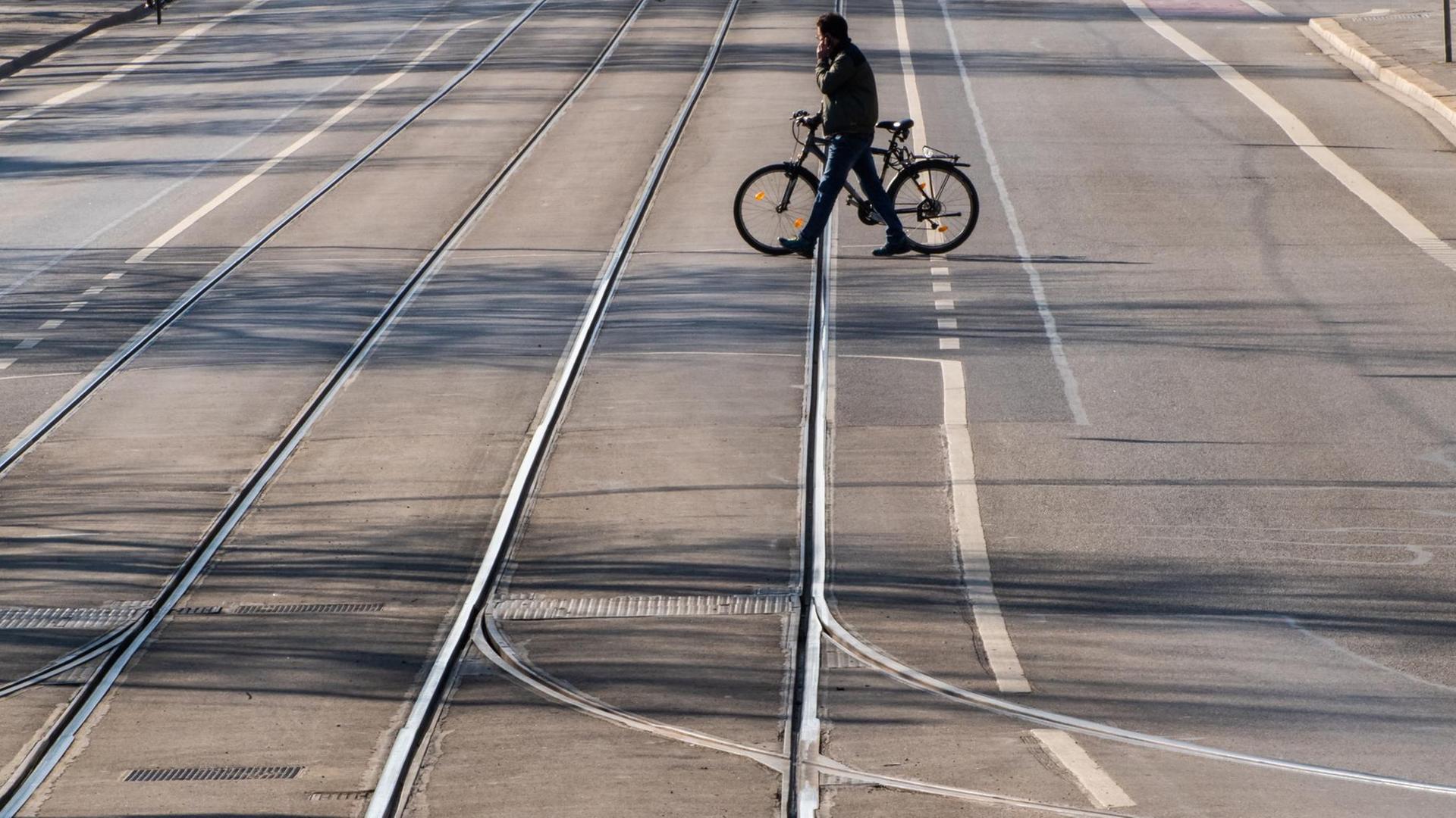 Ein Mann überquert mit einem Fahrrad eine leere Straße