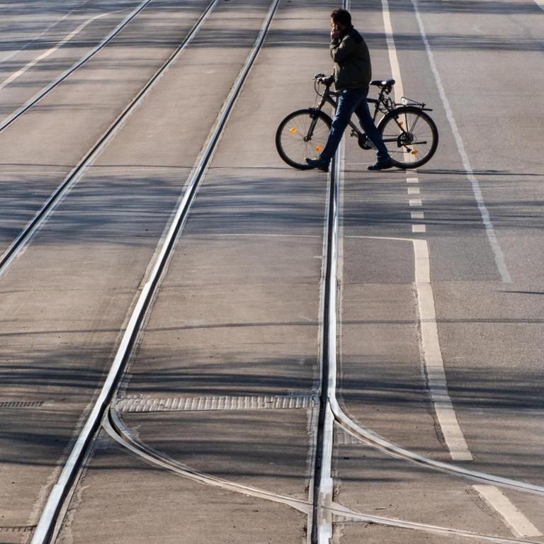 Ein Mann überquert mit einem Fahrrad eine leere Straße